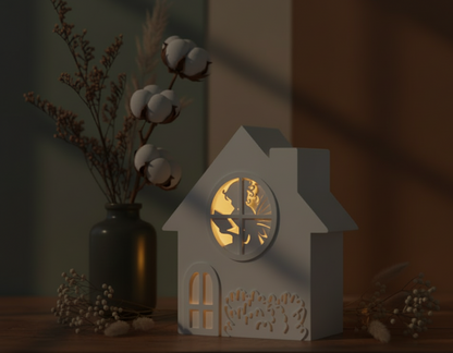 Weißes 3D gedrucktes Feenhaus mit LED-Teelicht, das warm durch ein rundes Fenster mit Feensilhouette scheint. Das Dekohaus steht auf einem Holzbrett, umgeben von sanfter Abendstimmung.