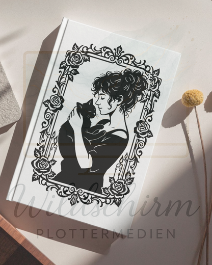 weißes notizbuch auf dem tisch. auf dem einband sieht man eine frau mit einer schwarzen katze 